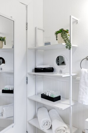 A bathroom with white shelves, a mirror, a towel rack, and a potted plant. - Agave - A Birdy Vacation Rental (San Antonio)