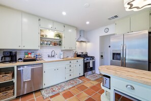A modern kitchen with white cabinets, a stainless steel refrigerator, a coffee maker, and a stove. - Agave - A Birdy Vacation Rental (San Antonio)