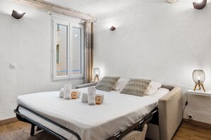 Ein modernes Schlafzimmer mit Bett, Nachttisch, Lampe und Blick nach draußen.