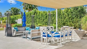 Une terrasse extérieure avec un canapé, des fauteuils et une table, le tout installé sous une pergola.
