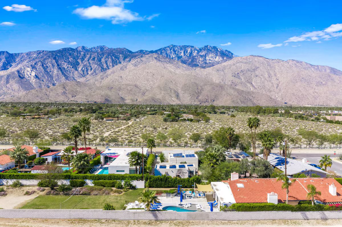 Un barrio residencial con casas, piscina y montañas al fondo.