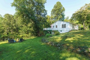 A white house with a covered porch, surrounded by lush greenery and trees. - Cozy Cottage Near Charlottesville & Wine Country (Charlottesville)