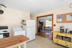 A compact kitchen with a stove, refrigerator, and a dining area with a table and chairs. - Cozy Cottage Near Charlottesville & Wine Country (Charlottesville)