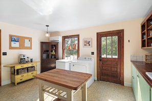A compact kitchen with a wooden table, a washing machine, and a coffee maker.