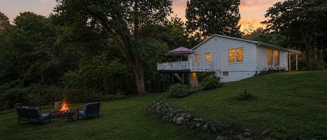 A house with a deck, a fire pit, and outdoor seating.