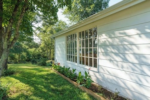 A house with a large window, surrounded by a well-maintained garden and trees.