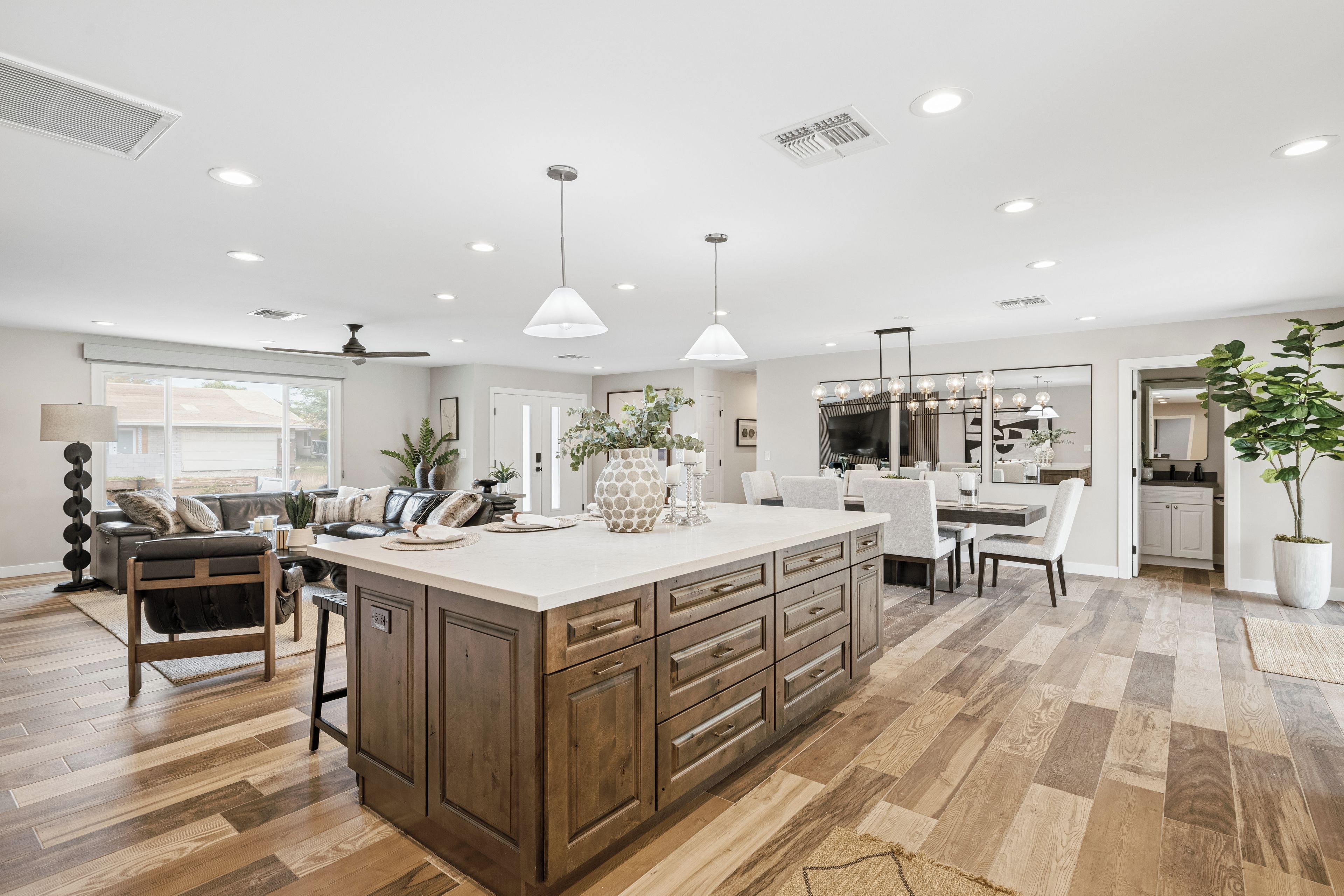 A modern kitchen with a large island, wooden cabinets, and a dining area with a table and chairs.