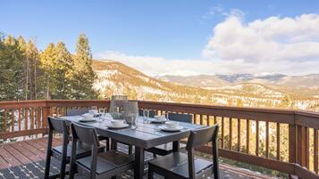 Mesa de comedor al aire libre con vistas a montañas y árboles.