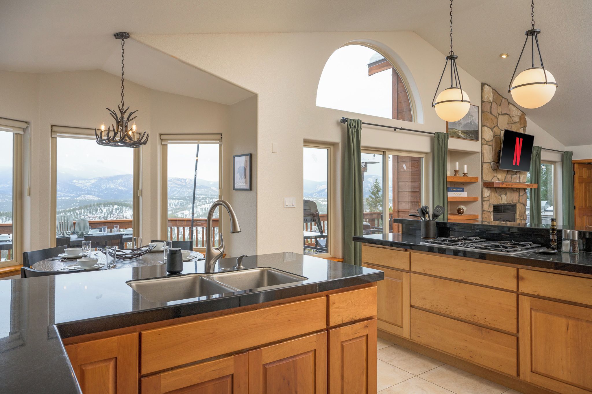 Una cocina moderna con una isla grande, electrodomésticos de acero inoxidable y una pared decorativa de piedra.