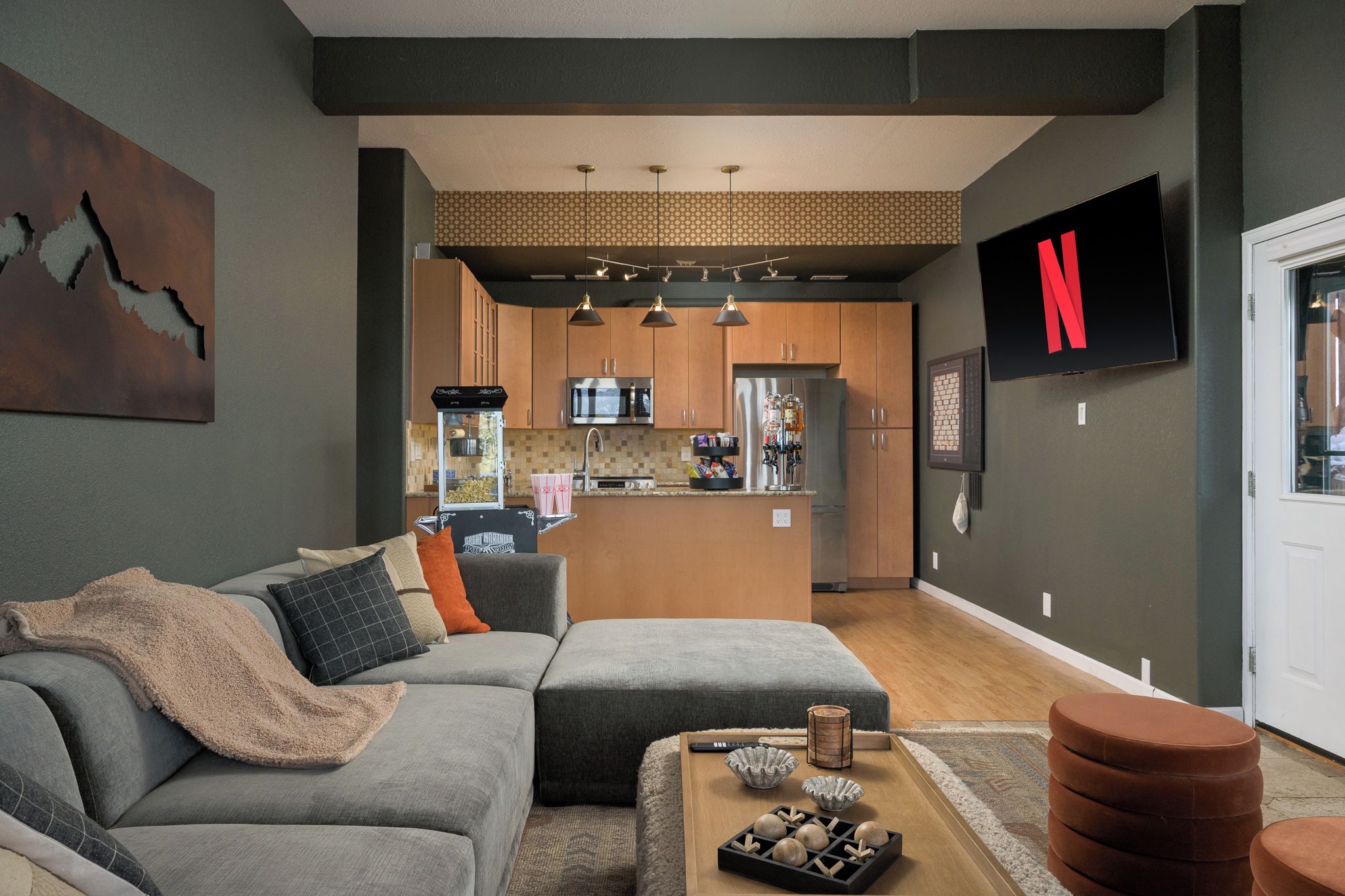 Uma sala de estar moderna com um sofá seccional, uma mesa de centro com objetos decorativos e uma TV fixada na parede.