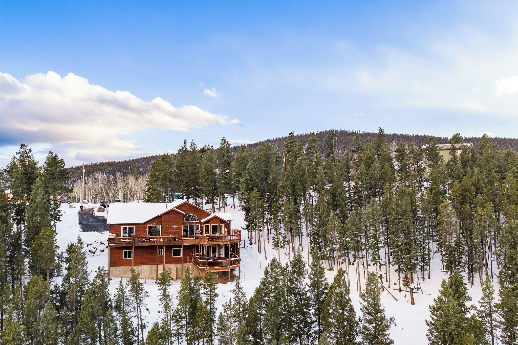 Una cabaña con fachada de madera, varios balcones y un bosque nevado al fondo.