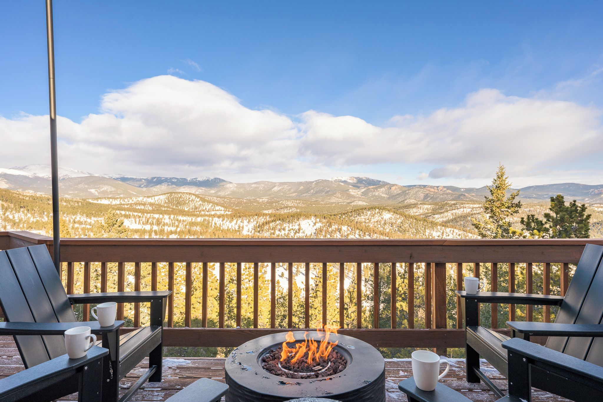 Una terraza con fogón, sillas y mesa, con vista a un paisaje montañoso.