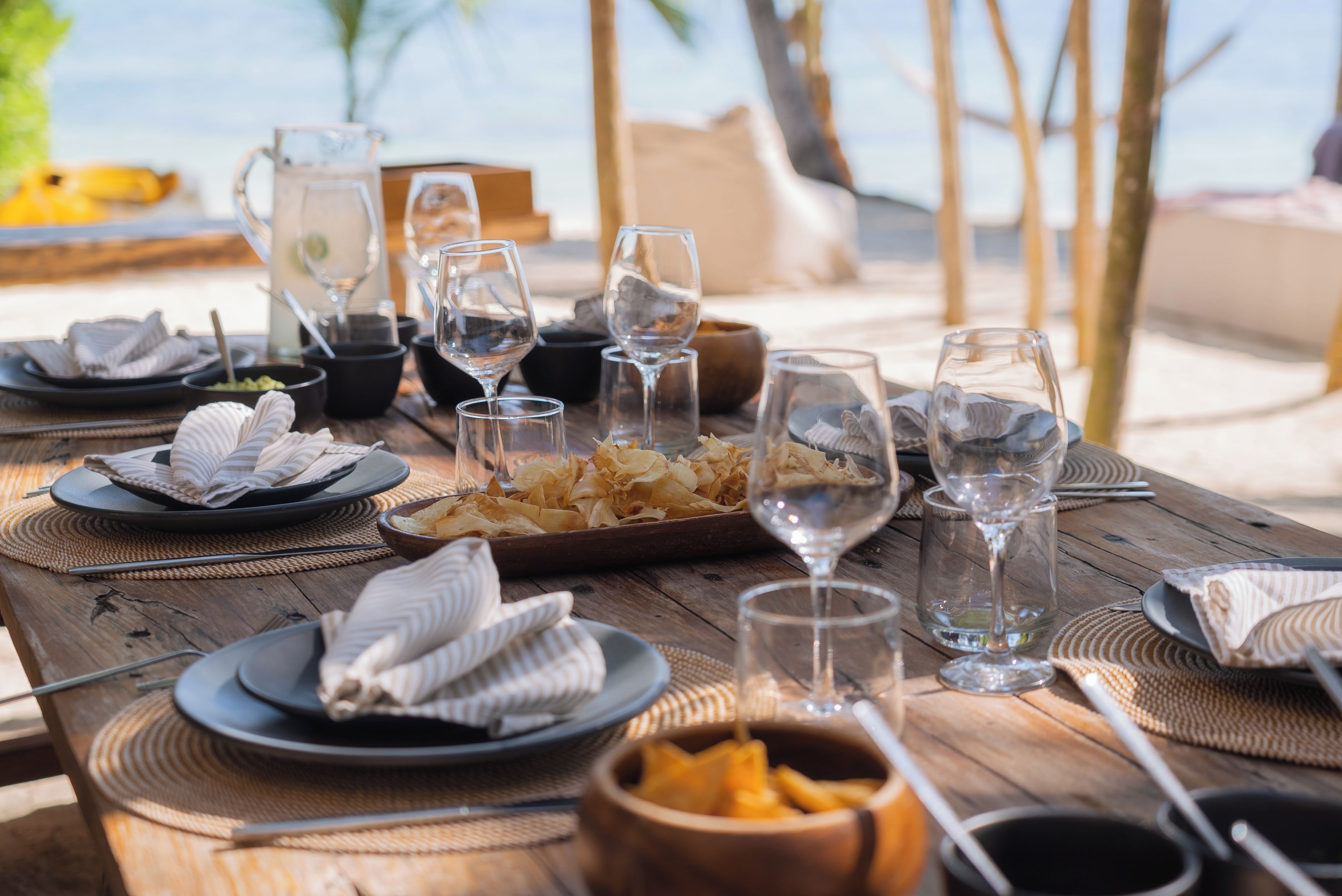 Una mesa de madera con platos, cuencos y vasos, que sugiere una disposición para comer.