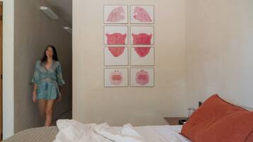 Un dormitorio con cama, mesita de noche y una pared decorada con seis obras de arte enmarcadas.