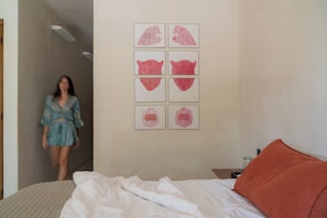 Un dormitorio con cama, mesita de noche y una pared decorada con seis obras de arte enmarcadas.