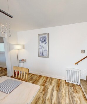 Ein Essbereich mit Tisch, Stühlen, einer Lampe und einem gerahmten Blumenbild an der Wand.