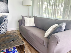 A living room with a grey sofa, a patterned armchair, a small wooden coffee table, and a floor lamp.
