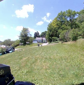 A grassy area with a house and trees in the background.