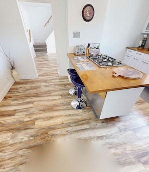 A kitchen with a wooden countertop, a gas stove, and a bar stool.