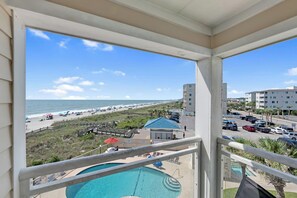 A balcony with a view of a beach, a pool, and a parking area. - Windy Hill Oceanfront Suite, Pool & Hot Tub (North Myrtle Beach)