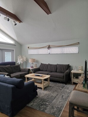 Ein Wohnzimmer mit einem grauen Sofa, einem blauen Sofa, einem Holztisch und einem grauen Teppich.