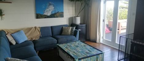 A living room with a blue sofa, a colorful coffee table, and a painting of a mountain.