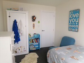 A bedroom with a bed, a bookshelf, a wardrobe, and a wall decoration.