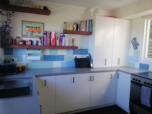 A kitchen with white cabinets, a toaster, a kettle, and a window with a view.