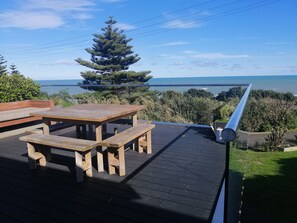 Eine Holzterrasse mit Picknicktisch und Bänken mit Blick auf ein Gewässer.