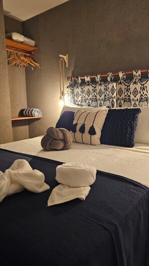 A neatly made bed with a dark blue bedspread, two pillows, and a folded towel. - Beach house in gated community São Miguel dos Milagres CASA MALÚ Alagoas (São Miguel dos Milagres)