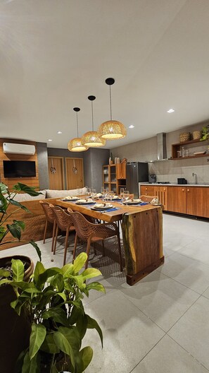Cozinha moderna com ilha central, armários de madeira e iluminação pendente.