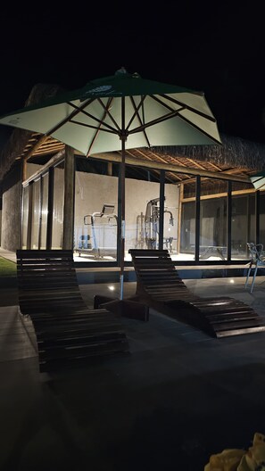 A covered outdoor area with a thatched roof, exercise equipment, and seating. - Beach house in gated community São Miguel dos Milagres CASA MALÚ Alagoas (São Miguel dos Milagres)