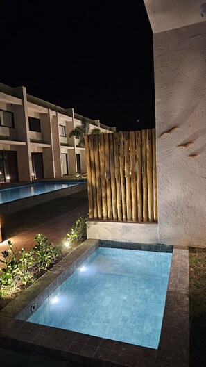 Piscina com cerca de madeira e um edifício ao fundo.