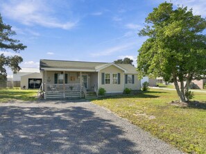 A single-story house with a front porch, a garage, and a small front yard. - Nook Hill | 3-bedroom, Pool, Dog-Friendly (Harkers Island)