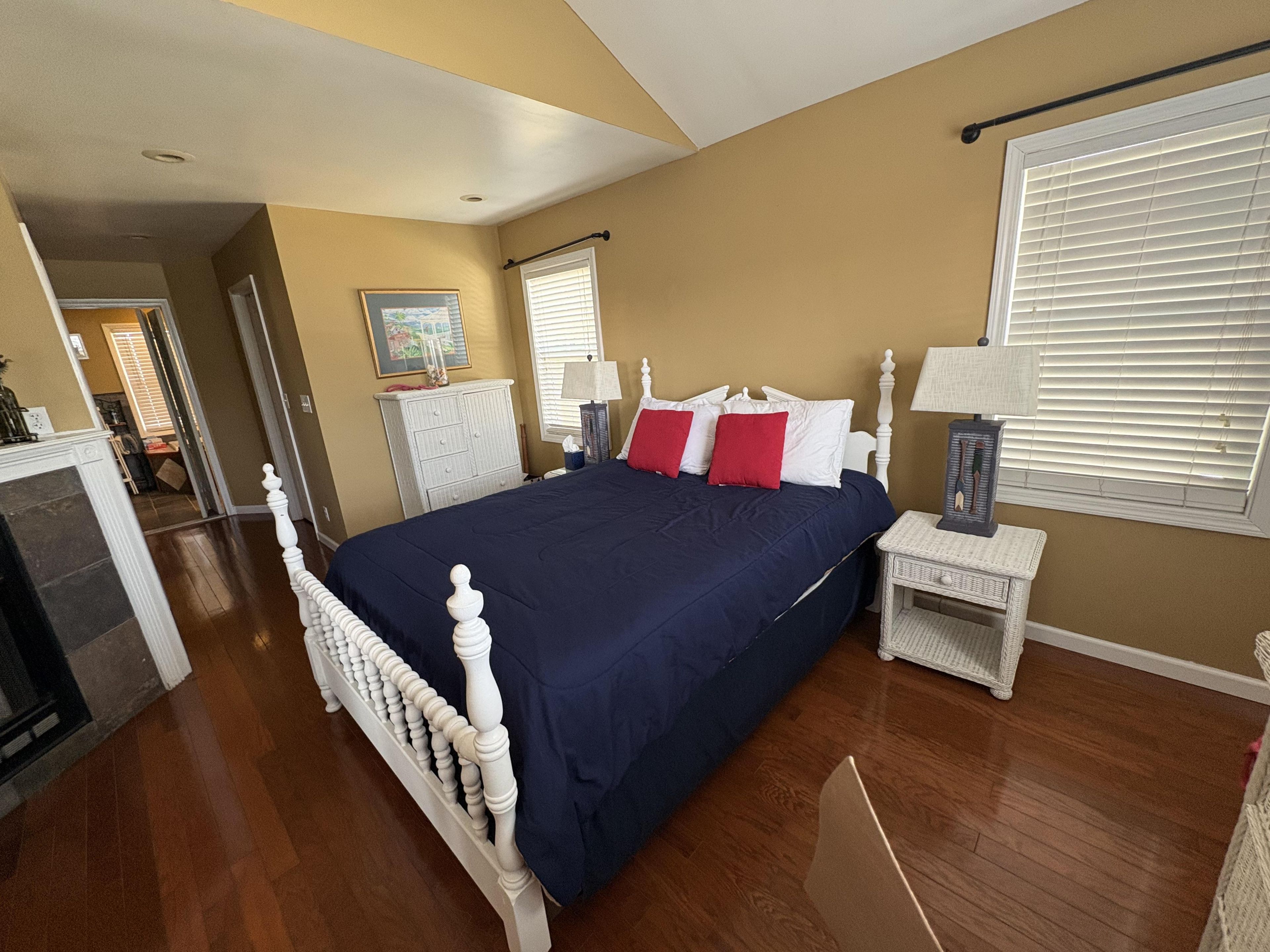 A bedroom with a large bed, a bedside table, a lamp, and a window with blinds.