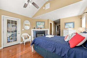 Une chambre à coucher avec un lit, une chaise, une cheminée et un ventilateur de plafond.