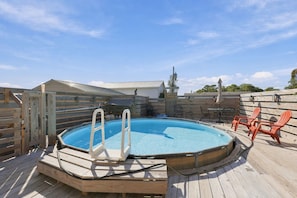 A wooden deck with a hot tub, surrounded by wooden fences and chairs. - Nook Hill | 3-bedroom, Pool, Dog-Friendly (Harkers Island)