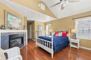 A bedroom with a bed, a fireplace, a ceiling fan, and a window with blinds. - Nook Hill | 3-bedroom, Pool, Dog-Friendly (Harkers Island)