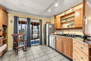 Une cuisine avec des meubles en bois, un réfrigérateur en acier inoxydable, un évier et un coin repas avec une chaise.