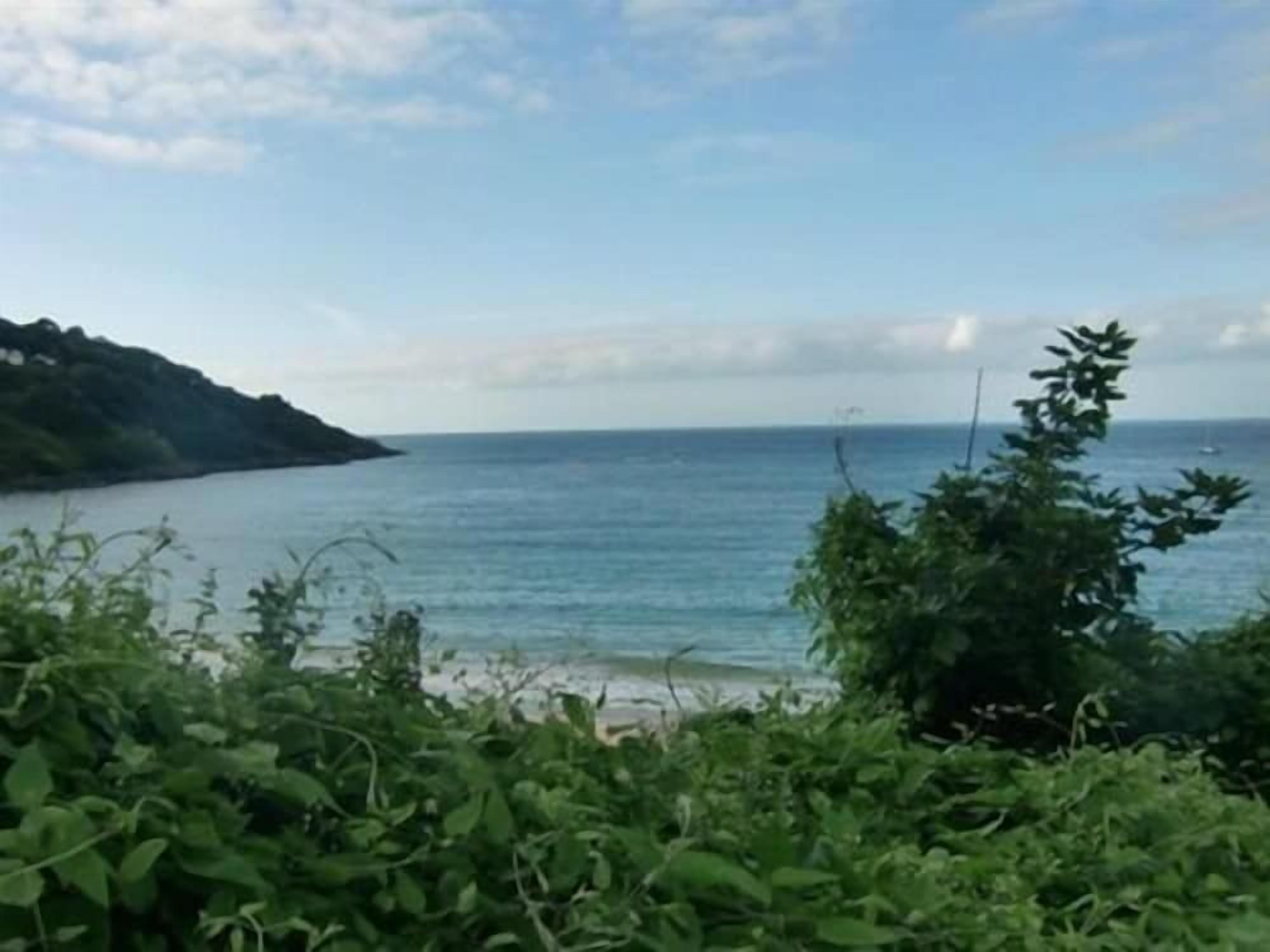 A coastal landscape with a view of the sea and a hill in the distance.
