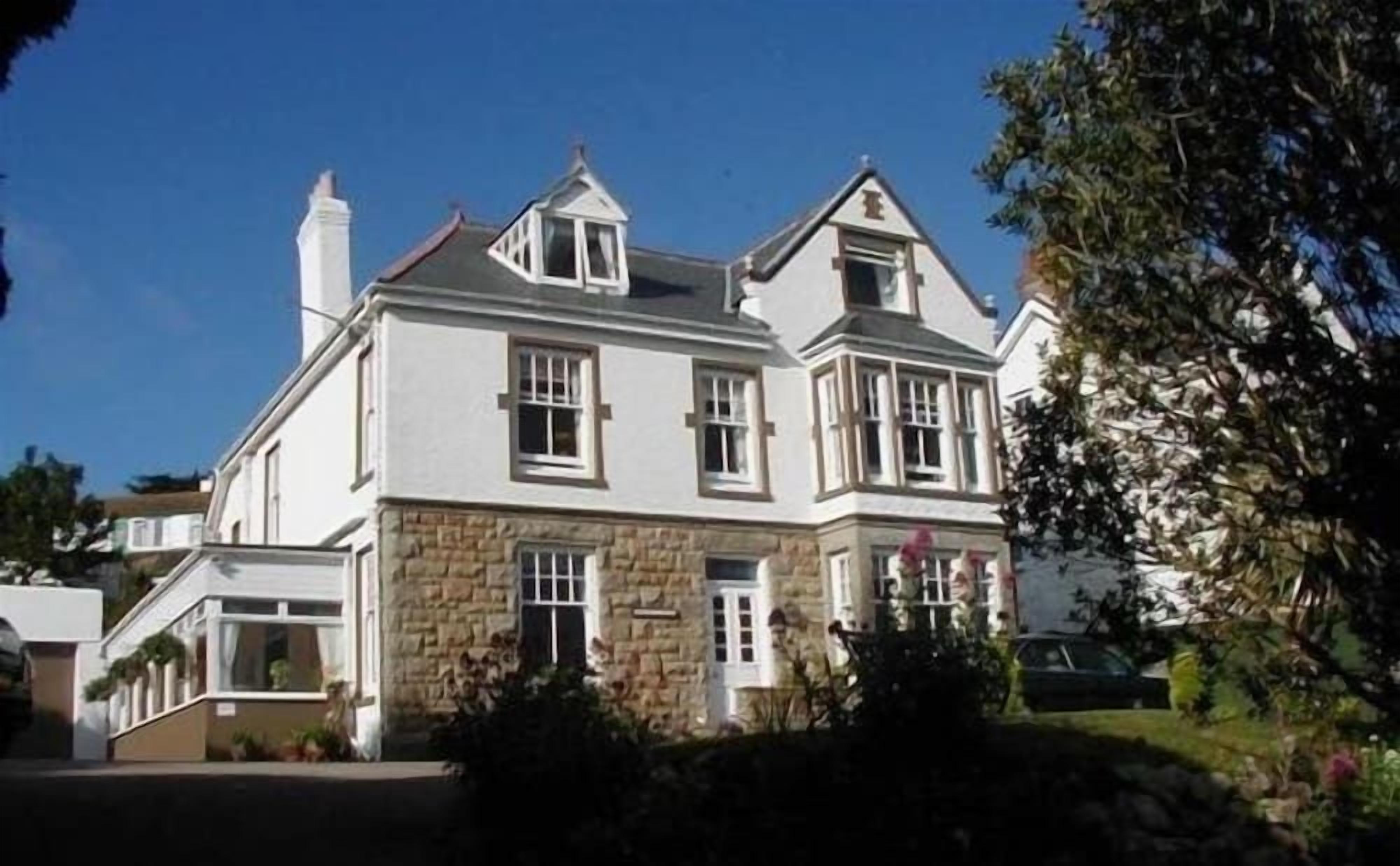 A two-story house with a stone facade, multiple windows, and a chimney.