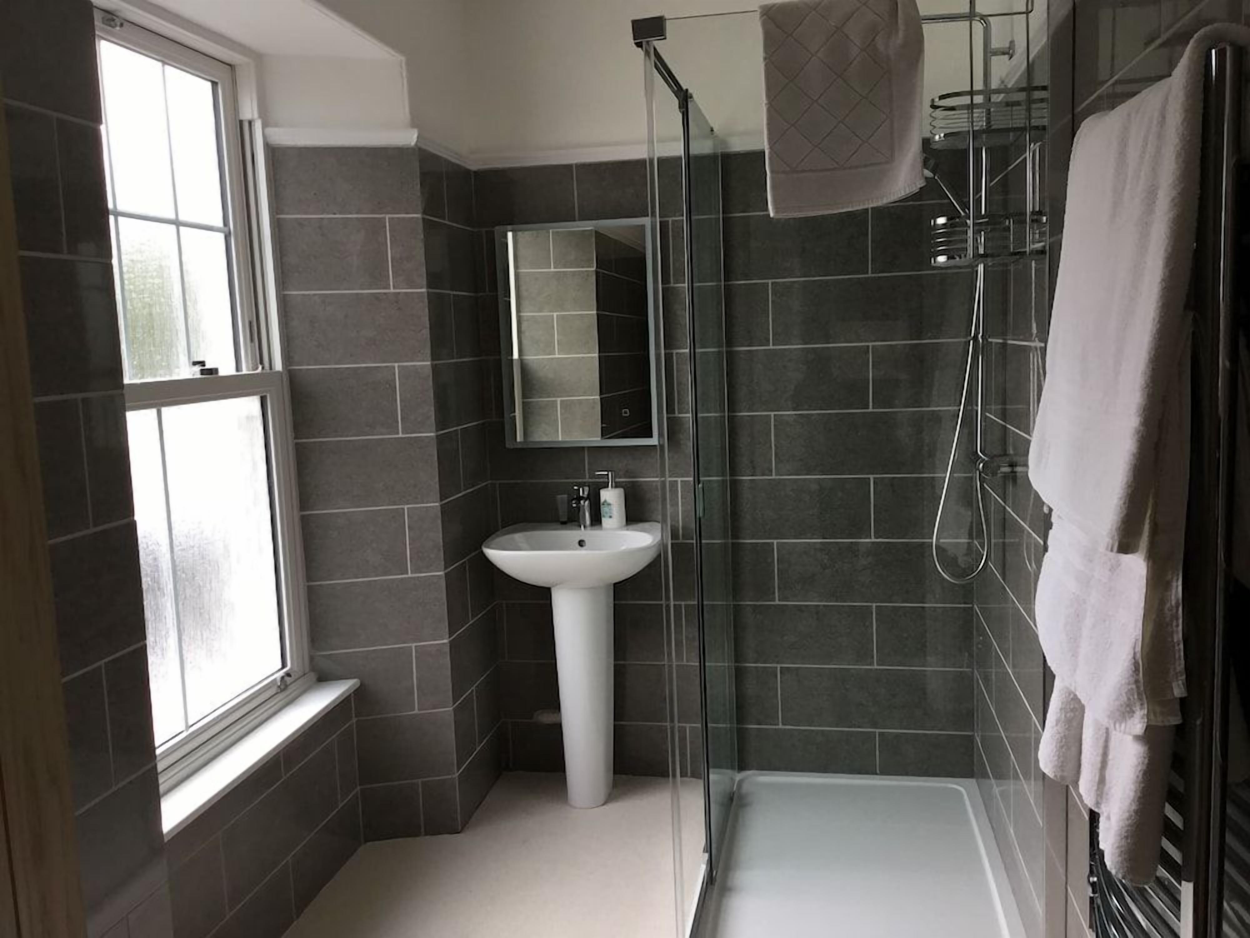 A bathroom with a shower, a sink, and a mirror.