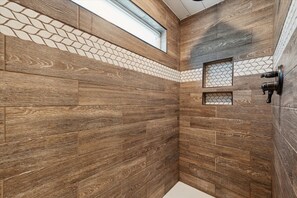 Un baño con paneles de madera, tragaluz y ducha con grifo.