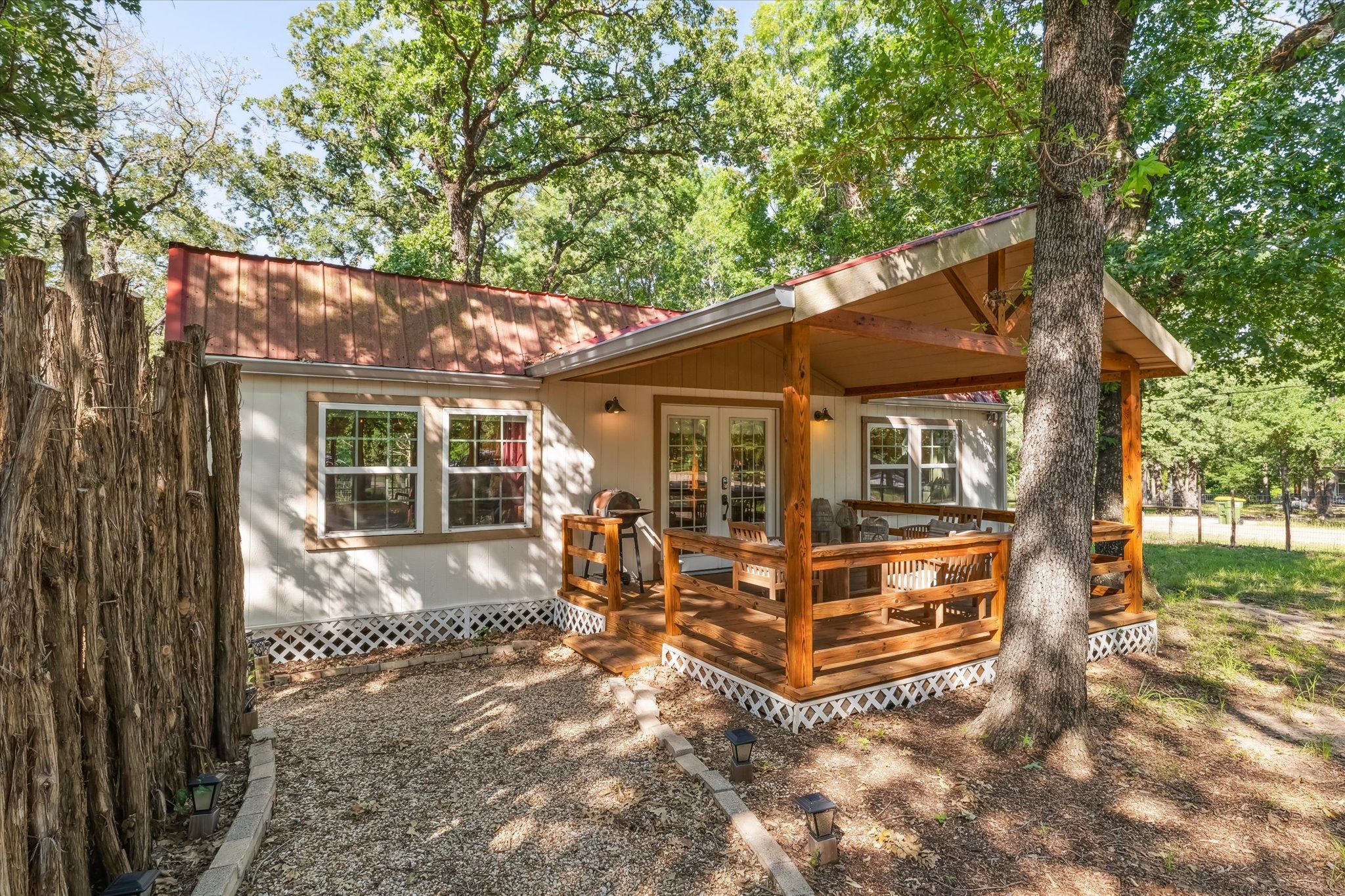 A cabin with a porch, windows, and a deck.