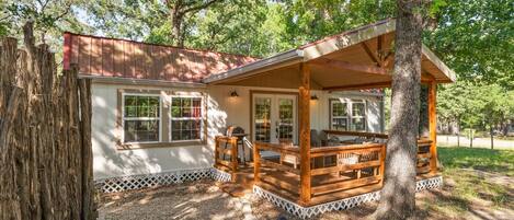 A cabin with a porch, windows, and a deck.