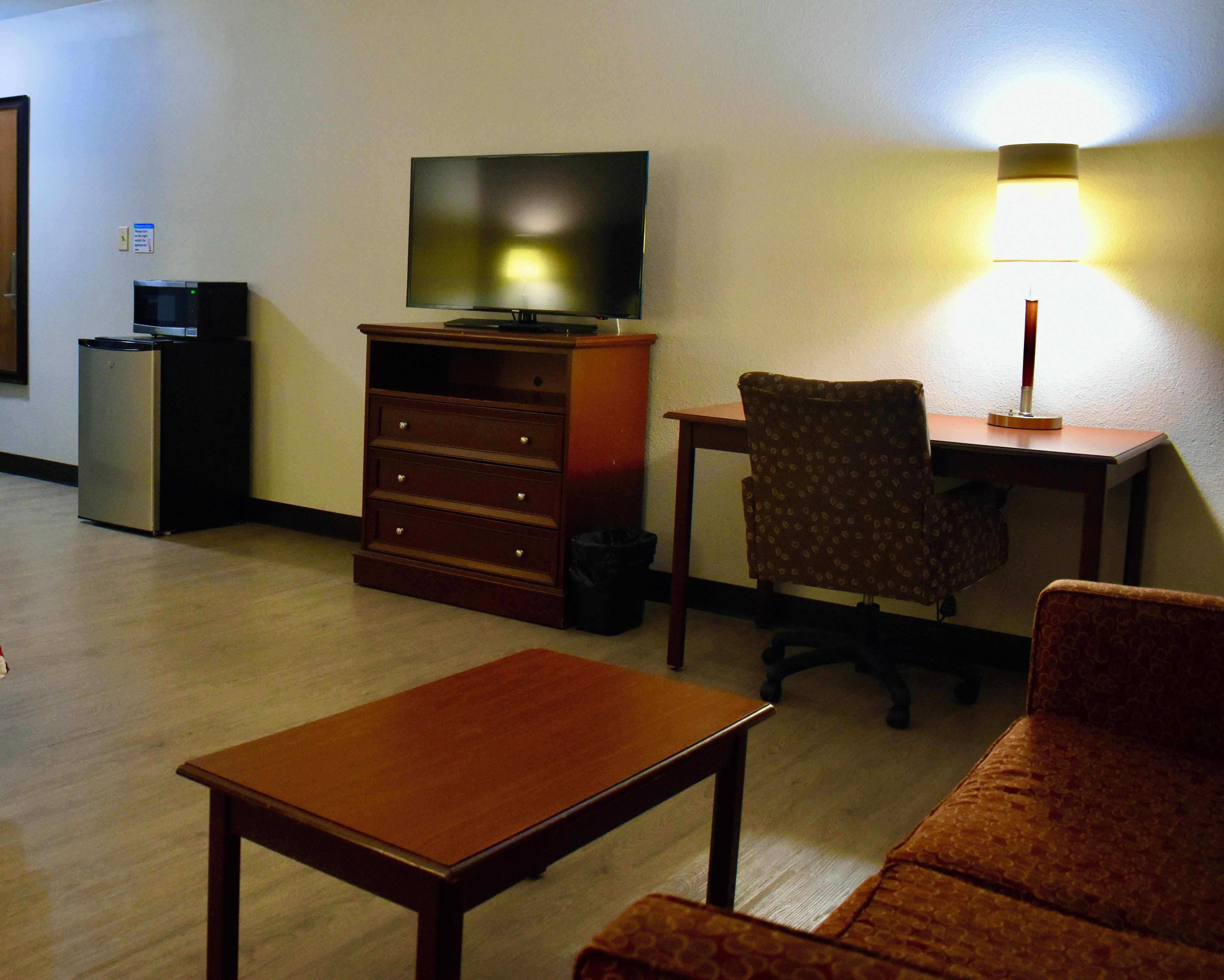 Une chambre d’hôtel équipée d’une télévision, d’un bureau, d’une chaise, d’un canapé et d’une petite table.