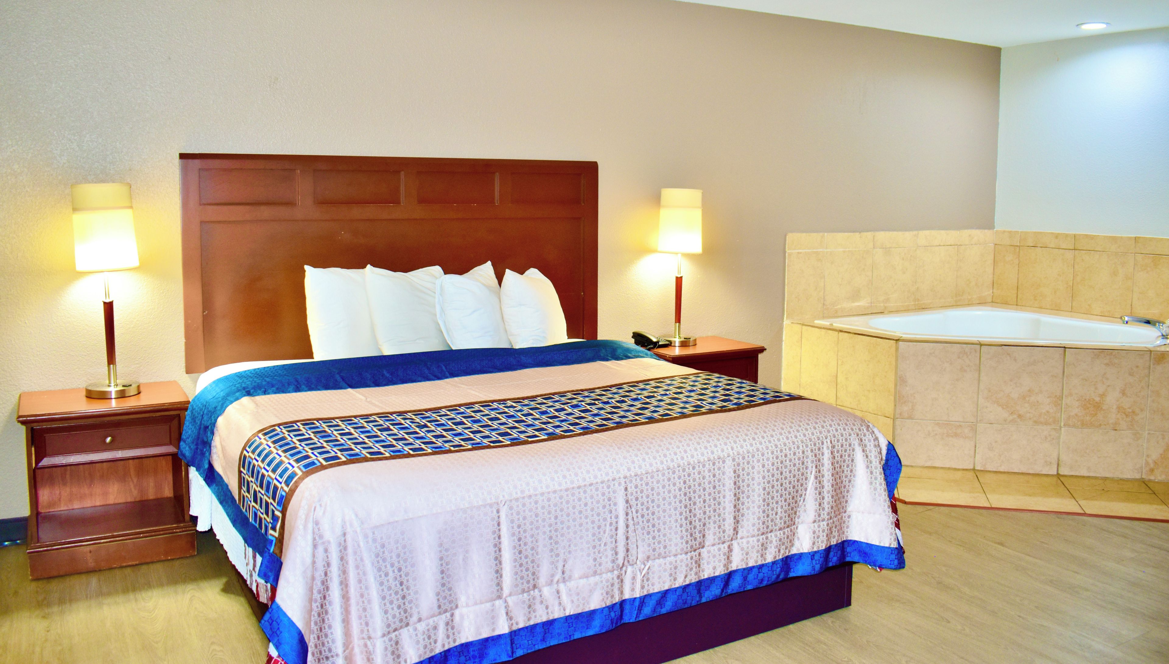 Una habitación de hotel con cama, lámparas de noche, teléfono y baño con bañera.