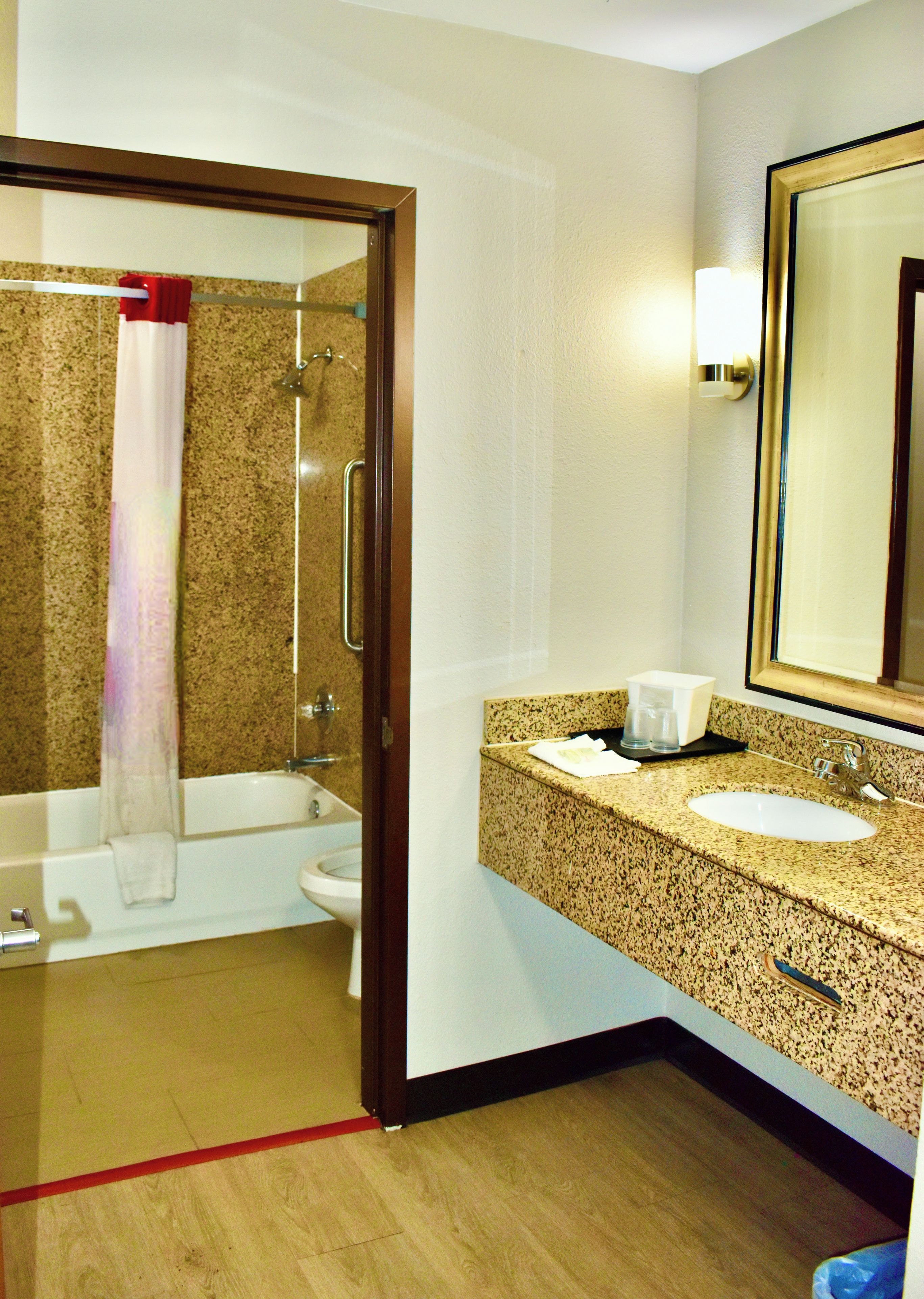 A bathroom with a shower, toilet, sink, and a mirror.