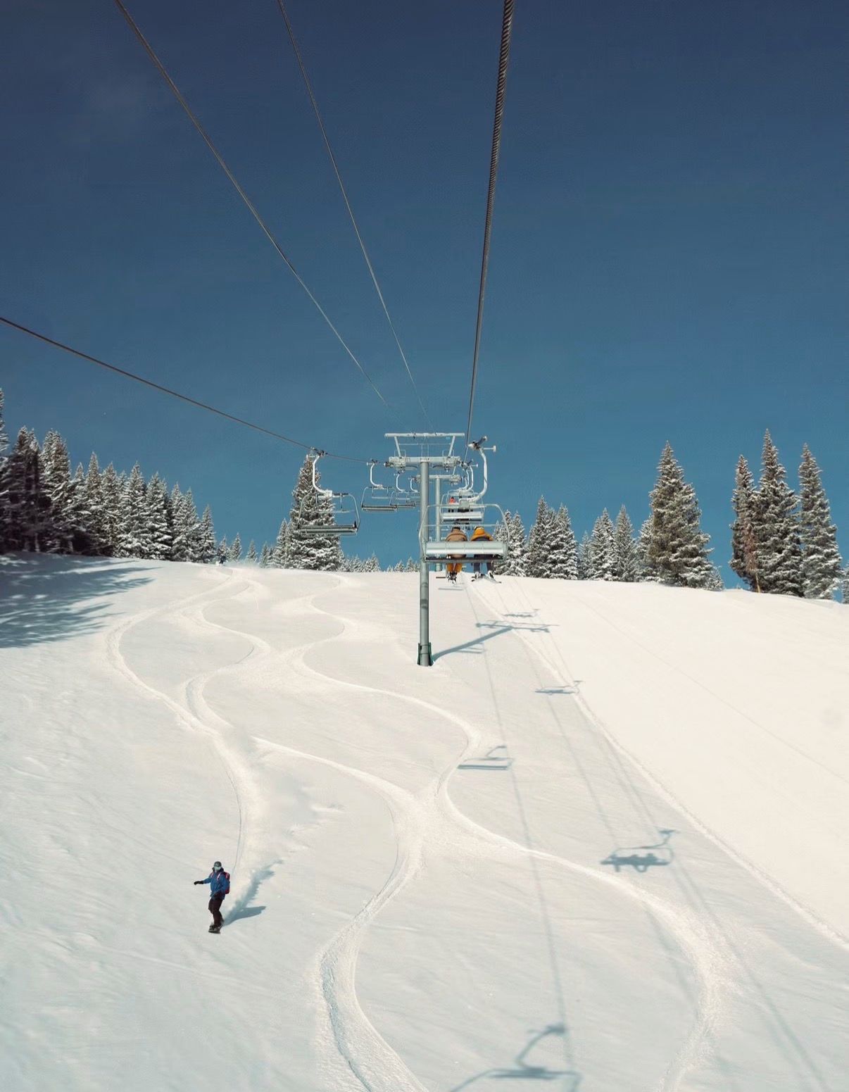 Eine Sesselbahn mit Sitz und einem Skifahrer auf der Piste.