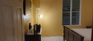A room with a bed, a desk with a computer, a lamp, and a window with blinds. - Sun-lit Arched Styled Villa with Scenic Mountain Views and Cool Tranquil Breeze (charlotte amalie)